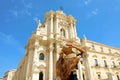 Beautiful young woman holding her hat and looking to Syracuse Cathedral, Sicily, Italy