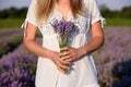 Beautiful young woman, holding lavender in a field on sunset