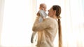 Beautiful young woman holding and lifting up her cute little baby. Concept of family happiness and parenting Royalty Free Stock Photo