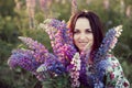 Beautiful young woman holding lupine flowers at sunset on field. concept of nature and romance. Royalty Free Stock Photo
