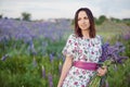 Beautiful young woman holding lupine flowers at sunset on field. concept of nature and romance. Royalty Free Stock Photo