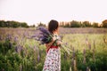 Beautiful young woman holding lupine flowers at sunset on field. concept of nature and romance. Royalty Free Stock Photo