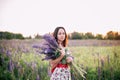 Beautiful young woman holding lupine flowers at sunset on field. concept of nature and romance. Royalty Free Stock Photo