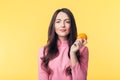 Beautiful young woman holding orange in hand isolated on yellow background Royalty Free Stock Photo