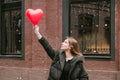 Beautiful young woman holding a red heart shaped ball, Valentine`s Day