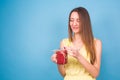 Beautiful young woman holding strawberry smoothie on blue background. Healthy organic drinks concept. People on a diet. Royalty Free Stock Photo