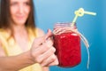 Beautiful young woman holding strawberry smoothie on blue background. Healthy organic drinks concept. People on a diet. Royalty Free Stock Photo