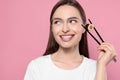 Beautiful young woman holding sushi roll with chopsticks on pink background Royalty Free Stock Photo