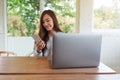 A young woman holding and using mobile phone with laptop computer on wooden table Royalty Free Stock Photo