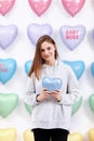 Beautiful young woman holds the blue balloon in the form of a heart. many hearts background. valentines day. baby shower.