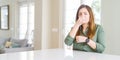 Beautiful young woman at home smelling something stinky and disgusting, intolerable smell, holding breath with fingers on nose Royalty Free Stock Photo