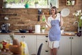 Beautiful young woman housewife wearing blue checkered apron standing in the kitchen holding a plate and showing her favourite Royalty Free Stock Photo