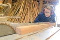 Beautiful young woman inspecting wood in workshop