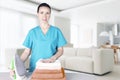 A beautiful young woman with an ironing board with an iron looks at the camera and smiles while ironing towels at home in the Royalty Free Stock Photo