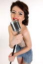 Beautiful young woman isolated on white in studio in old fashion clothes representing pinup and retro style with microphone Royalty Free Stock Photo