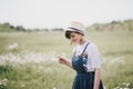 Beautiful young woman in a jeans dress and straw hat posing in a camomile field Royalty Free Stock Photo