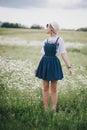 Beautiful young woman in a jeans dress and straw hat posing in a camomile field Royalty Free Stock Photo