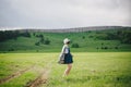 Beautiful young woman in a jeans dress and straw hat posing on a green meadow Royalty Free Stock Photo