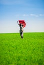 Beautiful young woman jumping on a green meadow with colored tissue Royalty Free Stock Photo