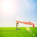 Beautiful young woman jumping on a green meadow with colored tissue Royalty Free Stock Photo