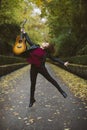 Beautiful young woman jumping with her guitar in a forest. Royalty Free Stock Photo