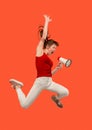 Beautiful young woman jumping with megaphone isolated over red background Royalty Free Stock Photo