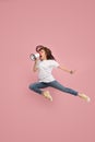 Beautiful young woman jumping with megaphone over pink background Royalty Free Stock Photo
