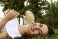 Beautiful young woman with large dandelion lying on green grass in park. Allergy free concept Royalty Free Stock Photo