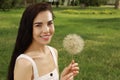 Beautiful young woman with large dandelion in park, space for text. Allergy free concept Royalty Free Stock Photo