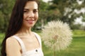 Beautiful young woman with large dandelion in park, focus on flower. Allergy free concept Royalty Free Stock Photo