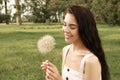 Beautiful young woman with large dandelion in park, space for text. Allergy free concept Royalty Free Stock Photo