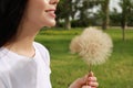 Beautiful young woman with large dandelions in park, closeup. Allergy free concept Royalty Free Stock Photo