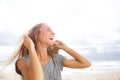 Beautiful young woman laughing at the beach with hand in hair Royalty Free Stock Photo