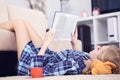 Beautiful young woman laying on the floor at home, reading a book, living room interior. Girl reading a book on the Royalty Free Stock Photo