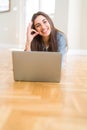 Beautiful young woman laying on the floor using laptop doing ok sign with fingers, excellent symbol Royalty Free Stock Photo