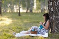 A beautiful young woman leaning against a tree knits. Royalty Free Stock Photo