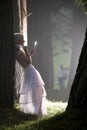 Beautiful young woman leaning against tree trunk in misty forest Royalty Free Stock Photo