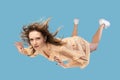 Beautiful young woman levitating in mid-air, falling down and her hair messed up soaring from wind