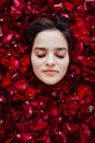 beautiful woman lies among the red petals of rose flowers Royalty Free Stock Photo