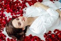 beautiful woman lies among the red petals of rose flowers Royalty Free Stock Photo