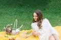 A beautiful young woman lies on a yellow blanket on the grass, holding a glass of wine Royalty Free Stock Photo
