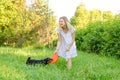 A beautiful young woman in a light dress is holding a flying disk that a cute dog clung to