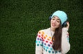 Beautiful young woman listening to music with headphones near grass wall. Royalty Free Stock Photo