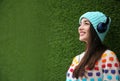 Beautiful young woman listening to music with headphones near grass wall. Royalty Free Stock Photo