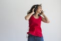 Beautiful young woman listening to music on her mobile phone with headset and having fun over white background. Casual clothing. Royalty Free Stock Photo