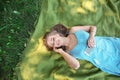 Beautiful young woman listening to music while lying on green grass outdoors Royalty Free Stock Photo