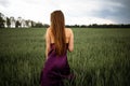 Beautiful young woman with long blonde hair in motion turned back, on the green field.Summer and freedom concept. Royalty Free Stock Photo