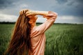 Beautiful young woman with long blonde hair in motion turned back, on the green field.Summer and freedom concept. Royalty Free Stock Photo