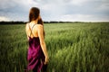 Beautiful young woman with long blonde hair in motion turned back, on the green field.Summer and freedom concept. Royalty Free Stock Photo