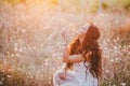 Beautiful young woman with long curly hair dressed in boho style dress posing in a field with dandelions Royalty Free Stock Photo